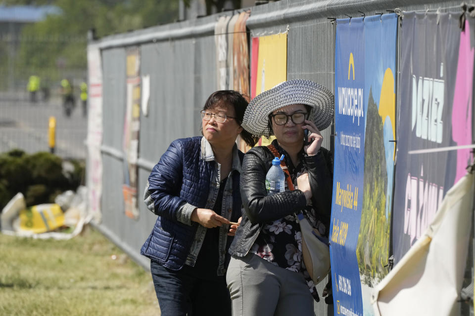 A members of Poland's Vietnamese community checks her phone in Warsaw, Poland, Wednesday, May 15, 2024, outside a shopping center destroyed in a weekend fire. A weekend fire in a shopping center in Warsaw dealt tragedy to many members of Poland's Vietnamese community. People lost entire livelihoods and say they don't know how they will manage to make a living. (AP Photo/Czarek Sokolowski)