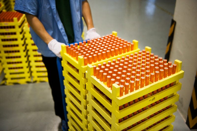 A factory worker pushes a cart of battery cells.