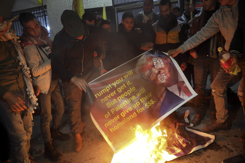 Palestinian burn a poster showing U.S. President Donald Trump as they protest the American peace plan in Bethlehem, Monday, Jan. 27, 2020. Israeli Prime Minister Benjamin Netanyahu arrived in Washington Sunday night vowing to "make history" at a planned meeting with President Donald Trump for the unveiling of the U.S. administration's much-anticipated plan to resolve the Israeli-Palestinian conflict. (AP Photo/Mahmoud Illean)