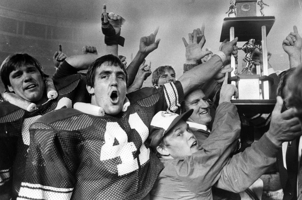 Glen Redd (41) and coach LaVell Edwards lead victory celebration around Holiday Bowl trophy after stunning win. Dec. 20, 1980.