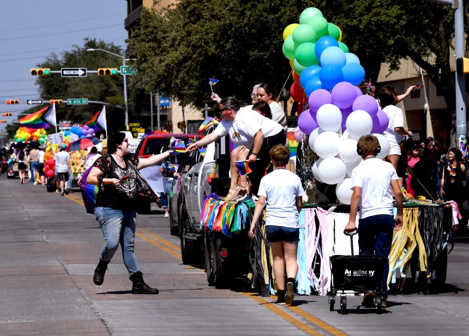 An attendee to Abilene's first Pride Parade receives a flag from a participant Saturday. The estimated size of the crowd was thought to approach 1,000 people.