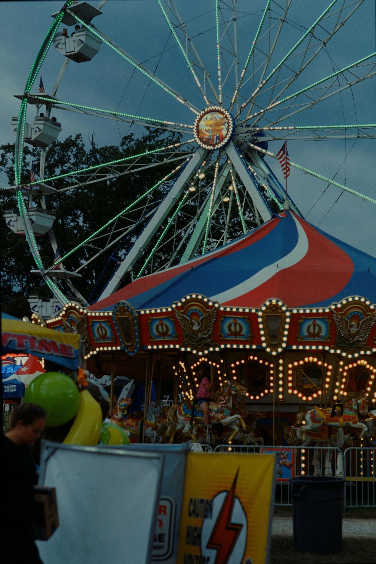 The lights on the ferris wheel and merry go round come on at the Addison County Fair & Field Days on Aug. 12, 2023, in Vergennes, Vermont.