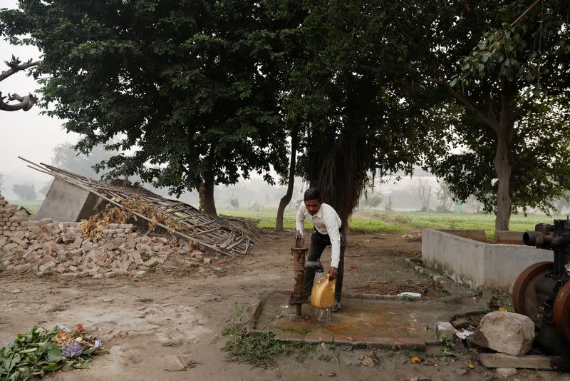 Totaram Maurya,45, a construction worker, fills water in a container using a handpump near his house on the Yamuna floodplains on a smoggy morning in New Delhi