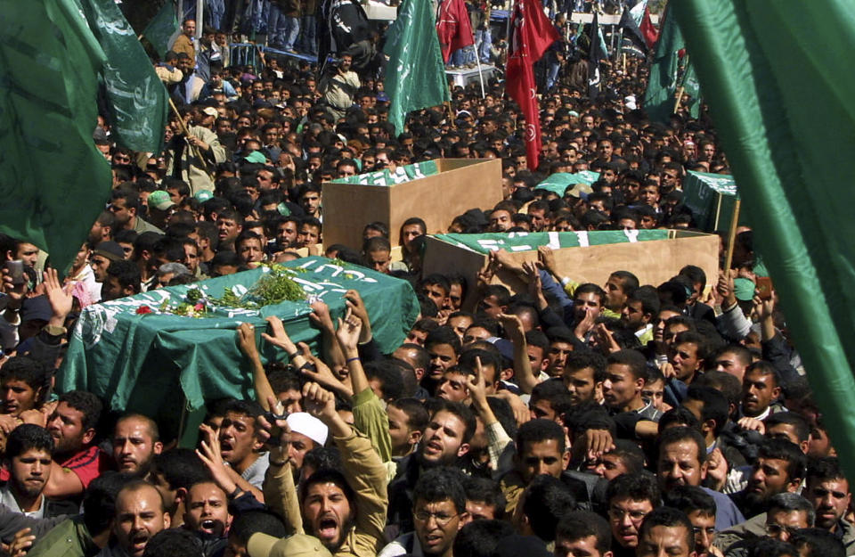 FILE - Thousands of Palestinian mourners carry the coffin of Hamas spiritual leader Sheik Ahmed Yassin, left,during his funeral in Gaza City, Monday, March 22, 2004. Yassin was killed in an Israeli helicopter strike while being pushed in his wheelchair. Prime Minister Benjamin Netanyahu and other Israeli leaders have repeatedly threatened to kill Hamas leaders following the group's deadly Oct. 7, 2023, cross-border attack that sparked the war in Gaza. Israel has a long history of assassinating its enemies, many carried out with precision airstrikes. (AP Photo/Khalil Hamra, File)