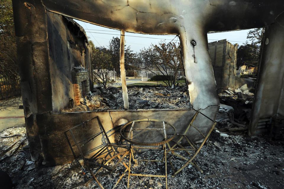 FILE - This Nov. 10, 2018 file photo shows a table and chairs outside one of at least 20 homes destroyed by the Woolsey fire on Wandermere Drive in the Point Dume area of Malibu, Calif. The number of structures destroyed by a huge Southern California wildfire has risen to 1,500. Another 341 structures were damaged as of a Monday, Nov. 20, 2018 count. As firefighters mop up, repair and restoration of utilities is continuing along with repopulation of areas evacuated when winds spread the fire earlier this month. Forecasters predict rain in the area by midweek. (AP Photo/Reed Saxon, File)