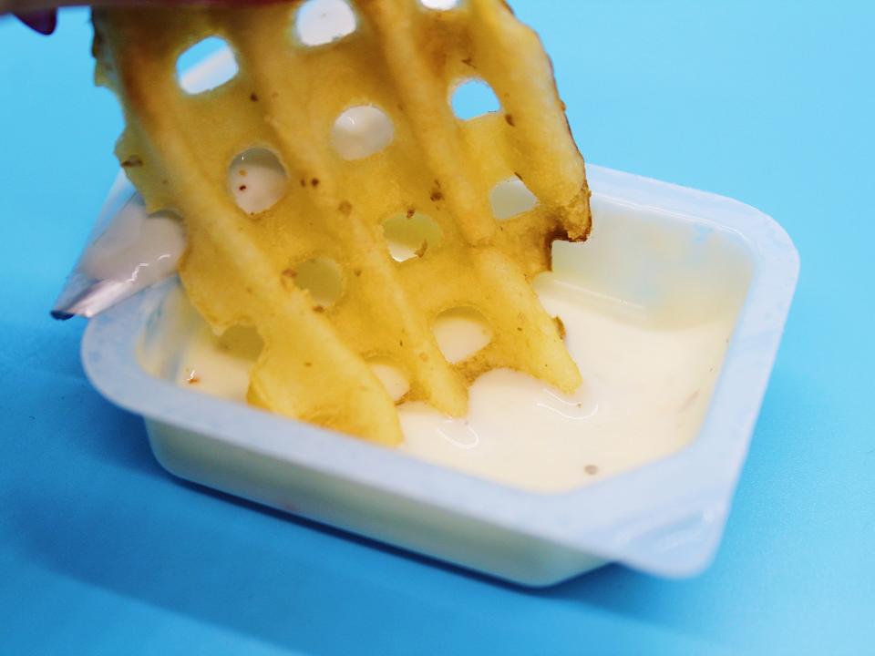 chick fil a waffle fries dipped in ranch sauce on blue background