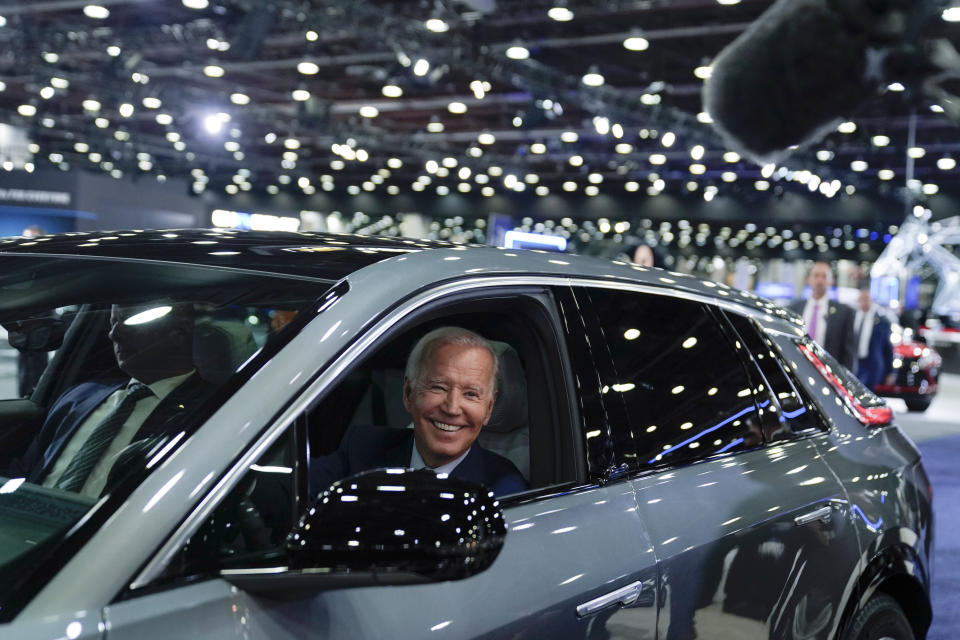 President Joe Biden smiles while driving a Cadillac Lyriq through the showroom.