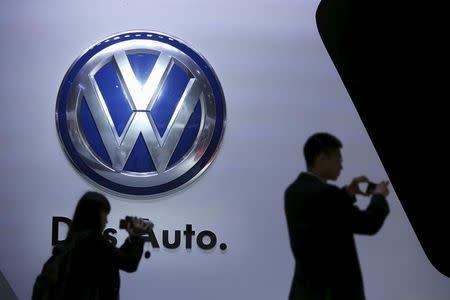 Guests stand next to a Volkswagen logo at the stage of the company at the 16th Shanghai International Automobile Industry Exhibition in Shanghai, April 20, 2015. REUTERS/Aly Song