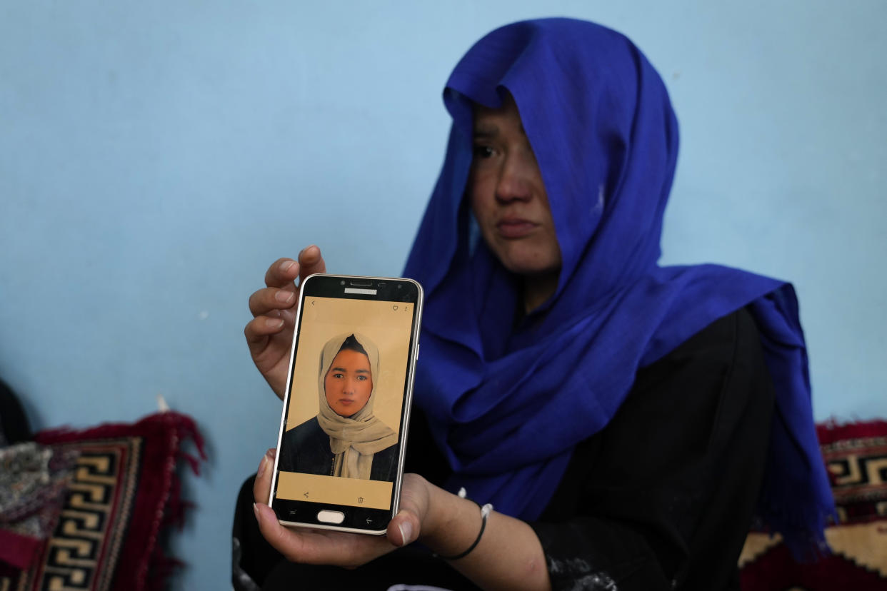 An Afghan girl shows a picture of her 19-years old sister who was victim of a suicide bomber, in Kabul, Afghanistan, Friday, Sept. 30, 2022. A Taliban spokesman says a suicide bomber has killed several people and wounded others at an education center in a Shiite area of the Afghan capital. The bomber hit while hundreds of teenage students inside were taking practice entrance exams for university, a witness says. (AP Photo/Ebrahim Noroozi)