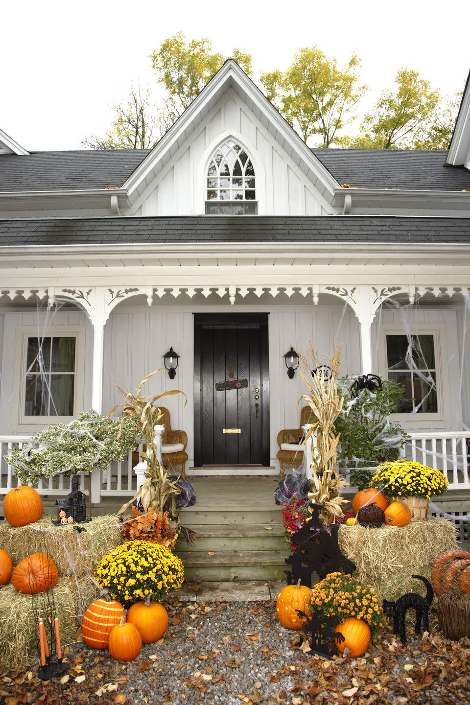 <p>Create a classic country Halloween vignette on your front porch by arranging hay bales, mums, pumpkins, and dried corn stalks around your steps. Fake spiderwebs add a not-too-scary touch. </p>