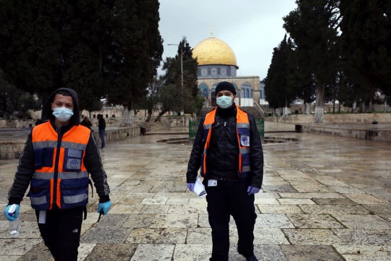 Palestinian volunteers, ready to offer cleaning gel to worshippers, walk in front of the Dome of the Rock in the compound known to Muslims as Noble Sanctuary and to Jews as Temple Mount, in Jerusalem's Old City