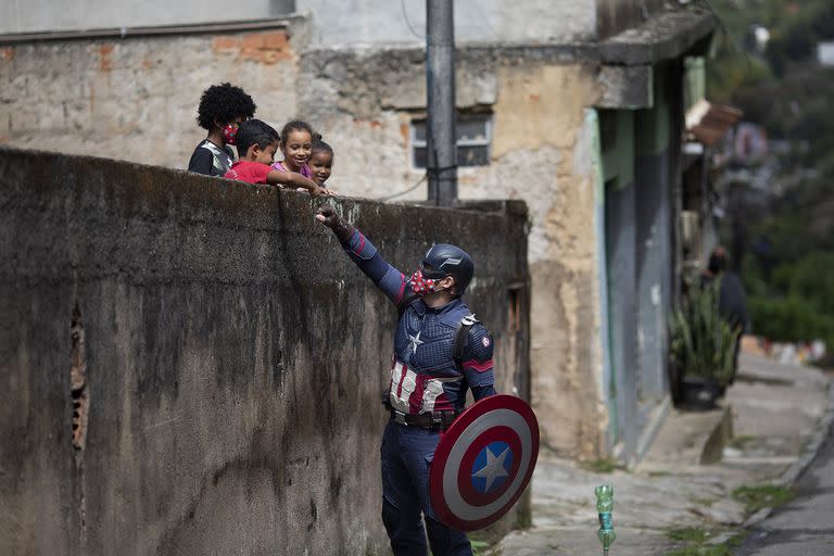 El policía militar Everaldo Pinto, vestido como el superhéroe Capitán América, saluda a los niños y los alienta a protegerse durante la pandemia de COVID-19 en Petrópolis, estado de Río de Janeiro, Brasil, el 15 de abril 