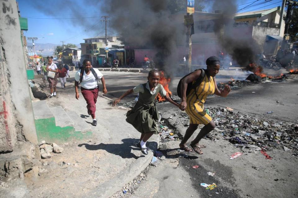 A woman and her daughter walk past a barricade that was set up by police officers amid civil disturbances in Port-au-Prince, Haiti, on Thursday, Jan. 26, 2023.