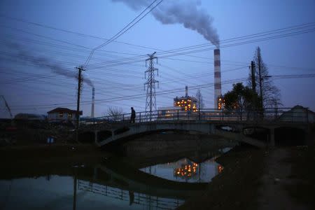 A man walks over a bridge as smoke rises from chimneys of a thermal power plant in Shanghai February 23, 2015. REUTERS/Carlos Barria