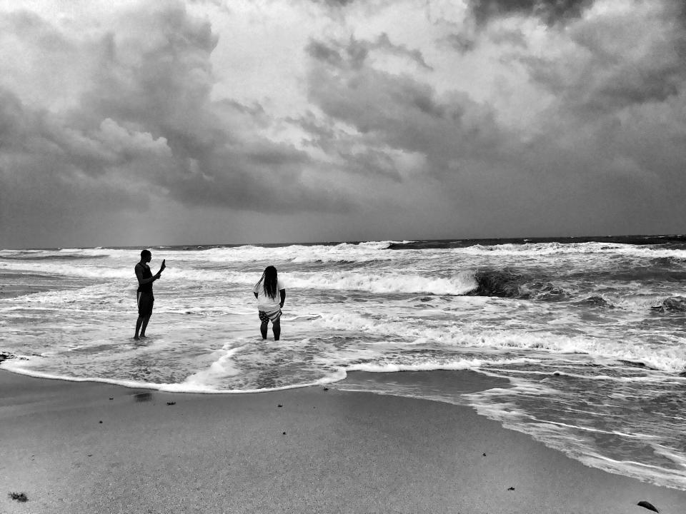 <p>Two men wade into a choppy ocean in the South Beach section of Miami Saturday. Visitors defied an evacuation order and strong winds and rain to see waves churned by Hurricane Irma. (Photo: Holly Bailey/Yahoo News) </p>