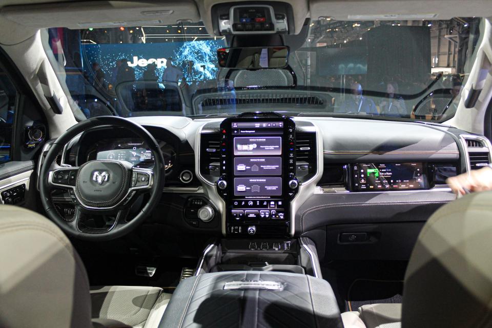 The interior of the 2024 Ram 1500 REV, including three screens and a steering wheel.