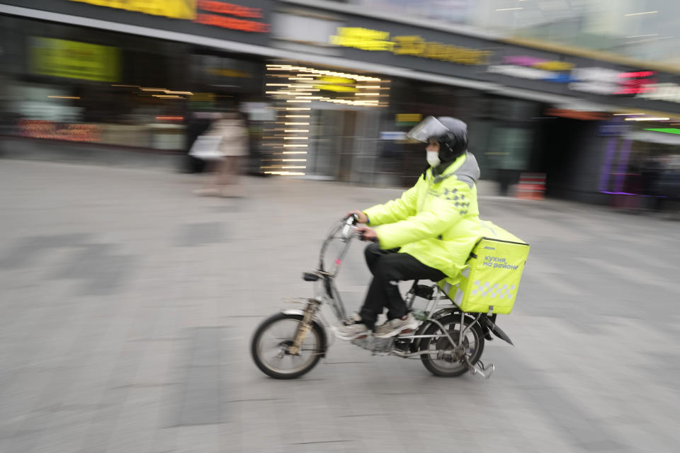 A food delivery courier rides a bicycle in Moscow, Russia, Friday, Oct. 29, 2021. Russia has recorded another record of daily coronavirus deaths even as authorities hope to stem contagion by keeping most people off work. Moscow introduced the measure starting from Thursday, shutting kindergartens, schools, gyms, entertainment venues and most stores, and restricting restaurants and cafes to only takeout or delivery. Food stores, pharmacies and companies operating key infrastructure remained open. (AP Photo/Pavel Golovkin)