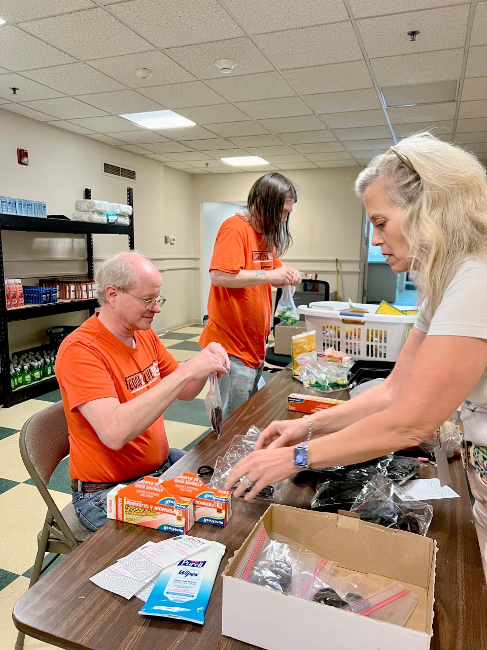 Volunteers Charlie Foreman, left, and Ted Kajencki help United Way's community education advocate Stacey Abeles pack hygiene products for delivery to a local school.