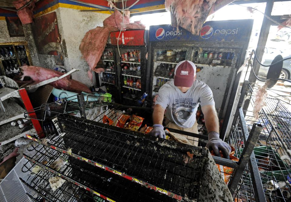 Matt Bogue works to salvage items from a gas station convenience store on in Tupelo, Miss., Tuesday, April 29, 2014. A dangerous storm system that spawned a chain of deadly tornadoes killed dozens from the Midwest to the Deep South. (AP Photo/Thomas Graning)