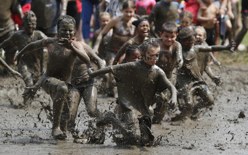 Kids participate in a running game through the mud during Mud Day at the Nankin Mills Park, Tuesday, July 9, 2019, in Westland, Mich. The annual day is for kids 12 years old and younger. While parents might be welcome, this isn't an event meant for teens or adults. It's all about the kids having some good, unclean fun during their summer break and is sponsored by the Wayne County Parks. (AP Photo/Carlos Osorio)