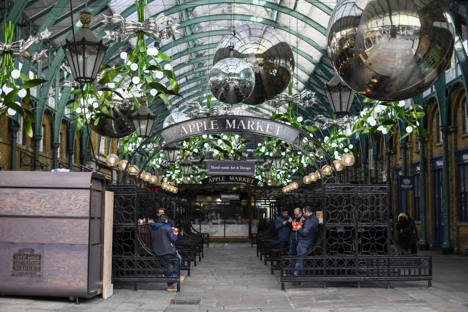 People eat at the closed stalls of Covent Garden Market, in London, Tuesday, Nov. 24, 2020. Haircuts, shopping trips and visits to the pub will be back on the agenda for millions of people when a four-week lockdown in England comes to an end next week, British Prime Minister Boris Johnson said Monday. (AP Photo/Alberto Pezzali)