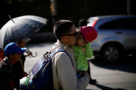 A man carries his daughter as a caravan of migrants departs from El Salvador en route to the United States, in San Salvador, El Salvador, October 28, 2018. REUTERS/Jose Cabezas