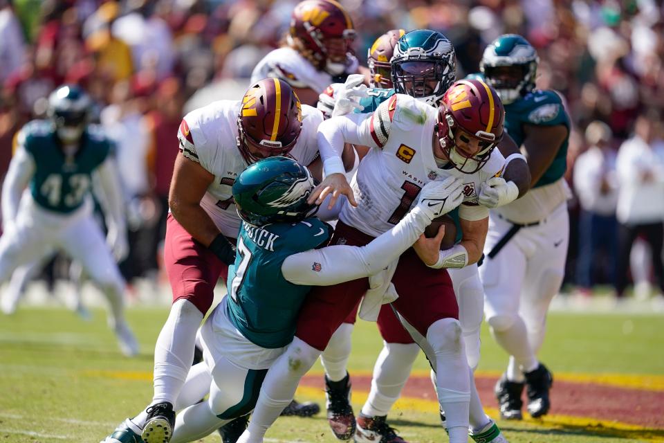 Washington Commanders quarterback Carson Wentz (11) is sacked by Philadelphia Eagles linebacker Haason Reddick (7) and defensive end Brandon Graham (55) during the first half of NFL football game, Sunday, Sept. 25, 2022, in Landover, Md.