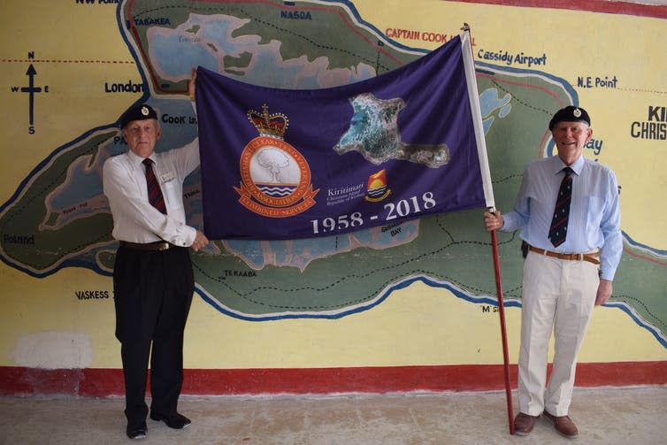 <span class="caption">Ron Watson and Robert McCann proudly hold their standard in front of a mural of Kiritimati Island.</span> <span class="attribution"><span class="source">B.Alexis-Martin, 2018</span></span>