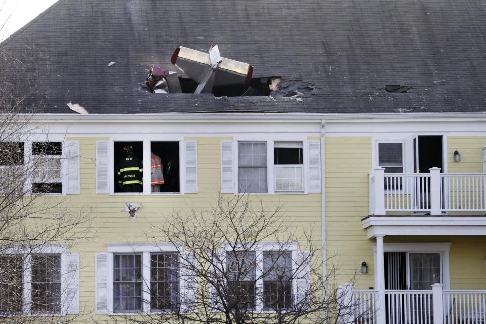 Firefighters investigate the scene after a small plane crashed into the roof of a condominium building across the Merrimack River from Lawrence Municipal Airport, Tuesday, Feb. 28, 2017, in Methuen, Mass. According to police, the pilot of the home-built plane was killed, while no one in the building was hurt. AP Photo/Elise Amendola)