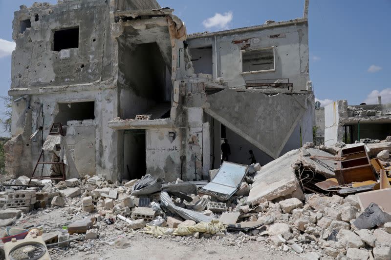 FILE PHOTO: Saher al-Ali's family members stand inside their damaged house in the rebel-held town of Nairab