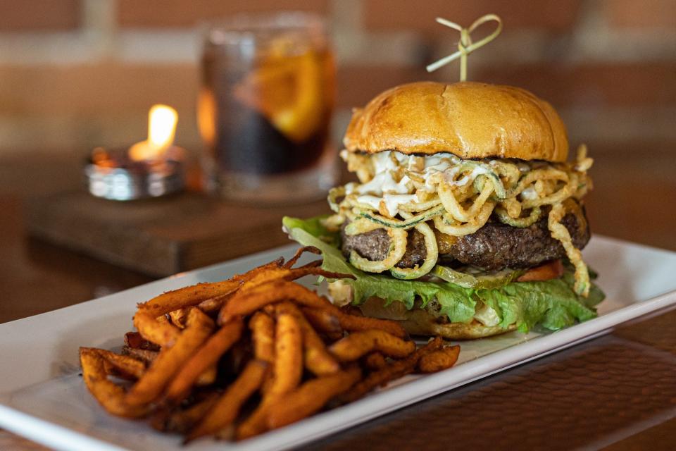 This signature burger is 8 ounces of premium blend of brisket, short rib and chuck, topped with aged cheddar, roasted garlic aioli and fried zucchini straws.