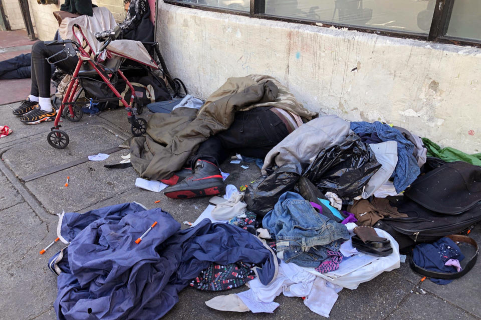 FILE - People sleep near discarded clothing and used needles on a street in the Tenderloin neighborhood in San Francisco, on July 25, 2019. The San Francisco Board of Supervisors approved an emergency order the mayor wants to tackle an opioid epidemic in its troubled Tenderloin district. (AP Photo/Janie Har, File)