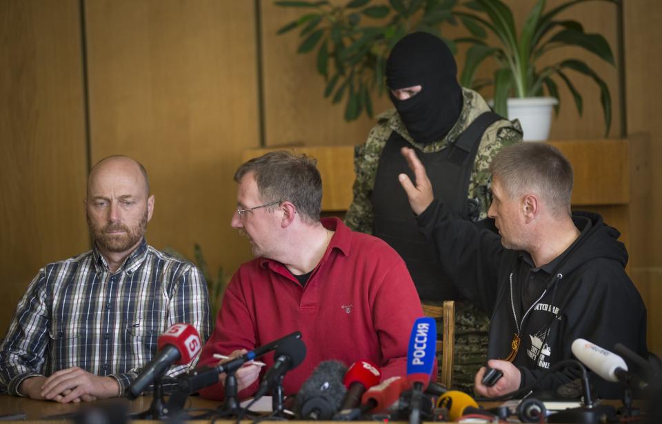 Vacheslav Ponomarev, the self-proclaimed mayor of Slovyansk, right, speaks to a pro-Russian gunman, as two of foreign military observer, one of them Axel Schneider of Germany, center, look to each other during a press conference in city hall, of Slovyansk, eastern Ukraine, Sunday, April 27, 2014. As Western governments vowed to impose more sanctions against Russia and its supporters in eastern Ukraine, a group of foreign military observers remained in captivity Saturday accused of being NATO spies by a pro-Russian insurgency. The German-led, eight-member team was traveling under the auspices of the Organization of Security and Cooperation in Europe when they were detained Friday. (AP Photo/Alexander Zemlianichenko)