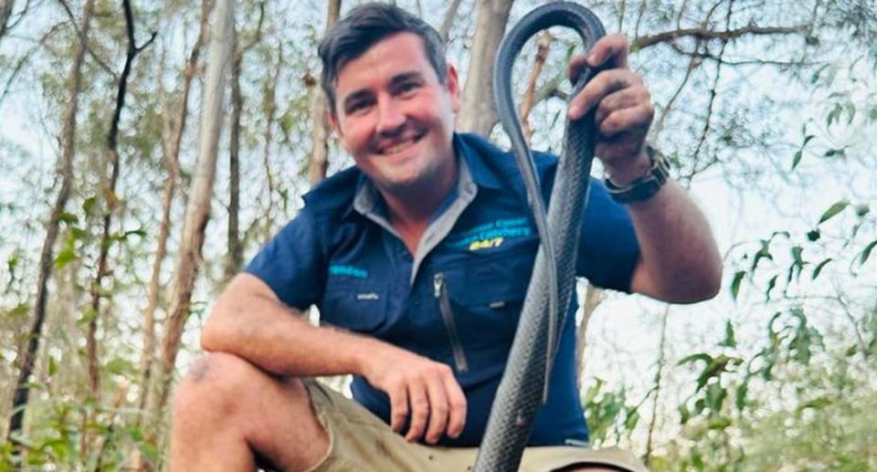 Snake catcher Brendon Gifford holding a large snake by its tail.