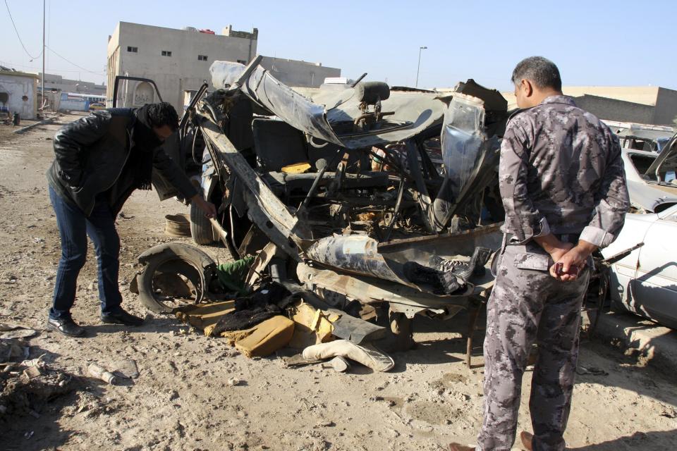 An Iraqi policeman (R) looks at a damaged vehicle after a car bomb attack in Baghdad 16, 2013. Suicide attacks and bombings across Iraq killed at least 21 people on Monday, medical and police sources said, the latest in a series of attacks that has brought violence in Iraq to its highest level in five years. (REUTERS/Wissm al-Okili)