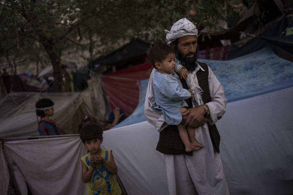 A displaced Afghan family waits for food donations at a camp for internally displaced persons in Kabul, Afghanistan, Monday, Sept. 13, 2021. (AP Photo/Bernat Armangue)