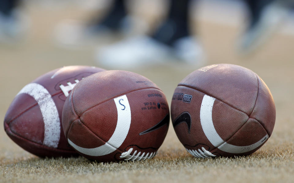 FILE - Footballs stand ready before the Virginia Tech at Wake Forest NCAA college football game in Winston-Salem, N.C., Saturday Oct. 15, 2011. A settlement being discussed in an antitrust lawsuit against the NCAA and major college conferences could cost billions and pave the way for a new compensation model for college athletes. (AP Photo/Bob Leverone, File)