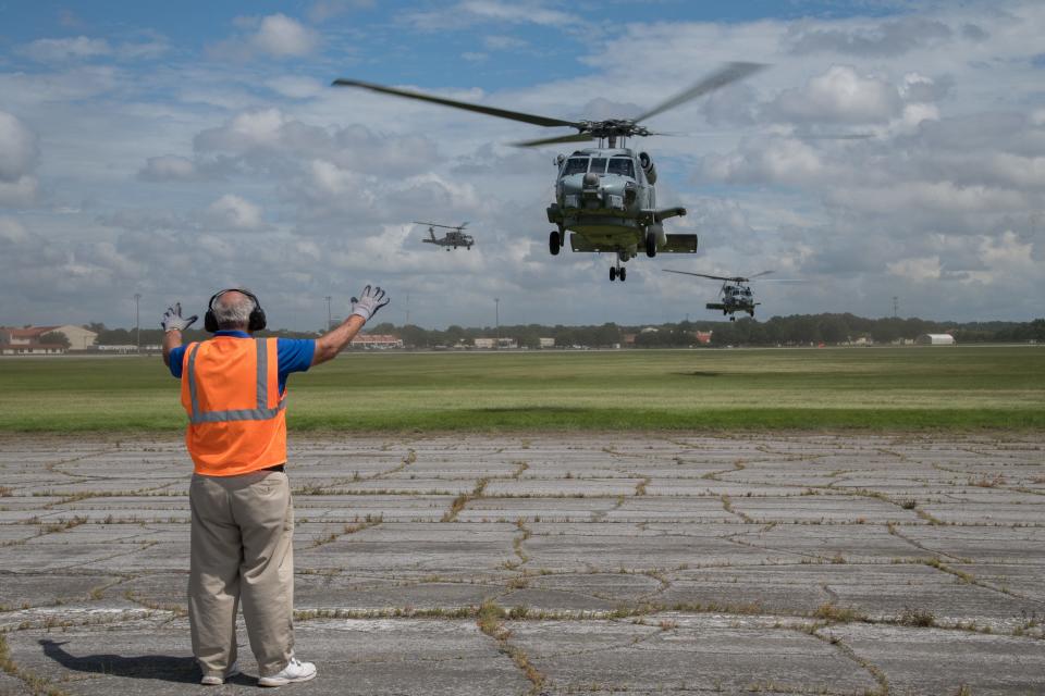 An Airman from the 42nd Operational Support Squadron directs U.S. Navy MH-60R Sea Hawk helicopters as they arrive at Maxwell Air Force Base in Montgomery, Ala., from Naval Air Station Jacksonville and Naval Station Mayport in Florida. The helicopters evacuated from the Jacksonville area in advance of Hurricane Dorian.