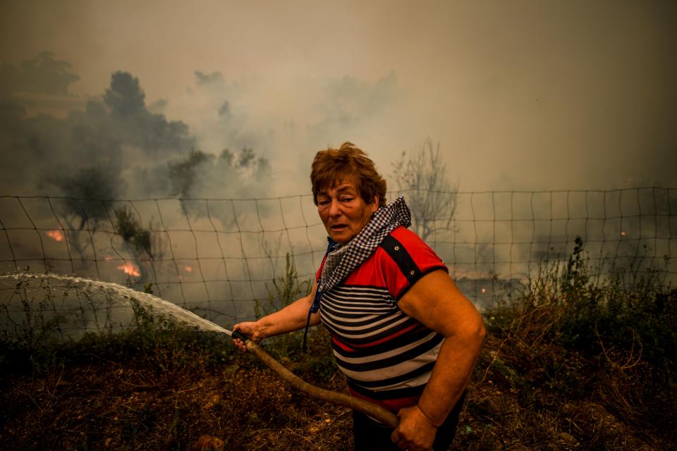 A villager uses a water hose to put out flames during a wildfire in Roda village in Macao, central Portugal on July 21, 2019. (Photo:Patricia De Melo Moreira/AFP/Getty Images)