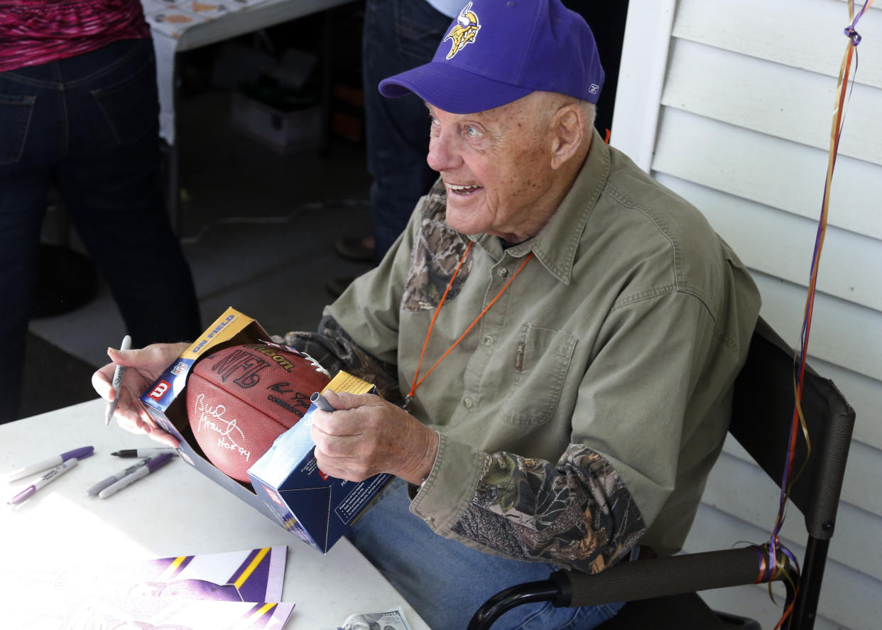 Former Minnesota Vikings NFL football coach Bud Grant signed a football as he celebrates his 88th birthday, Wednesday, May 20, 2015, while hosting a garage sale at his Bloomington, Minn. home. (AP Photo/Jim Mone)