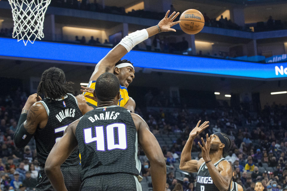 Sacramento Kings center Richaun Holmes, left, and forward Harrison Barnes (40) guard against Golden State Warriors center Kevon Looney, top left, during the first quarter of an NBA basketball game in Sacramento, Calif., Sunday, Oct. 24, 2021. (AP Photo/Randall Benton)