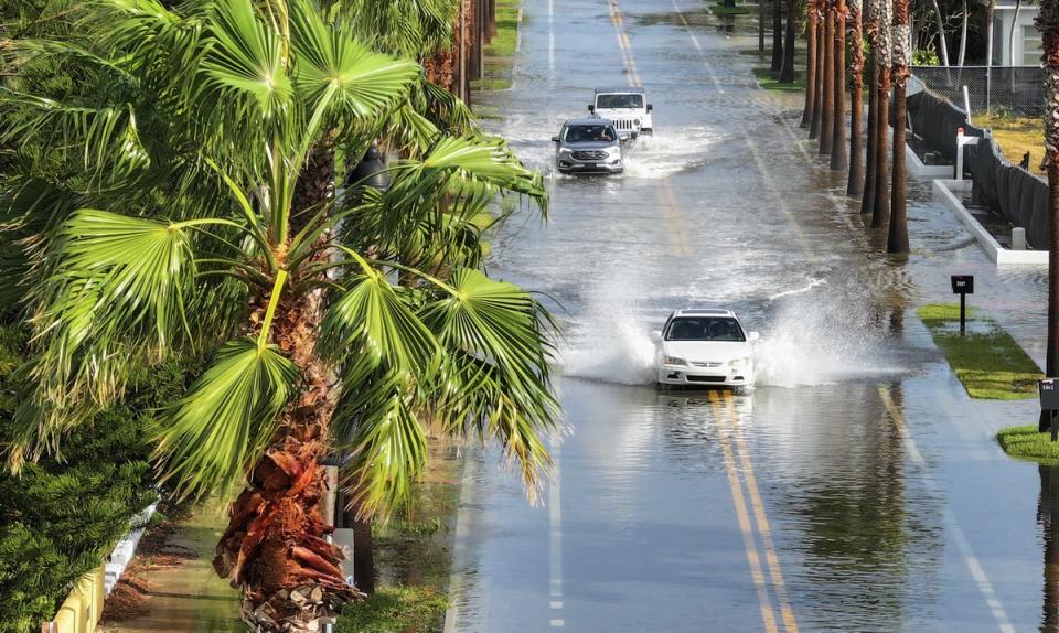 <p>Vehicles drive through a flooded street as Hurricane Helene churns offshore in St. Pete Beach, Florida</p> (Getty Images)