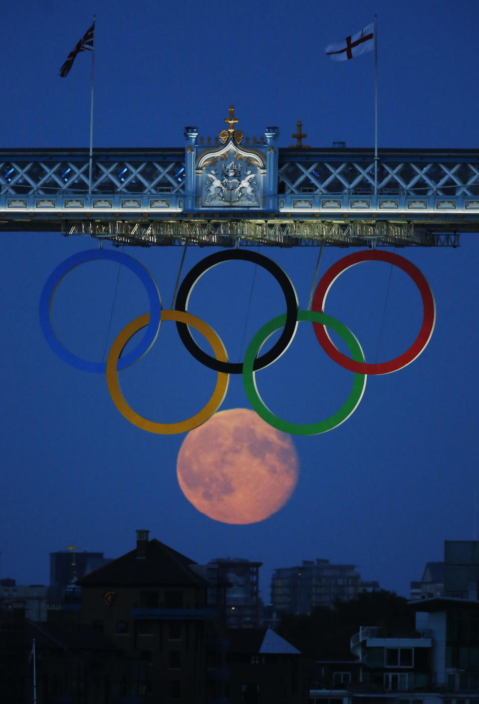 The full moon rises through the Olympic Rings hanging beneath Tower Bridge during the London 2012 Olympic Games August 3, 2012. REUTERS/Luke MacGregor (BRITAIN - Tags: SPORT OLYMPICS ENVIRONMENT CITYSPACE)