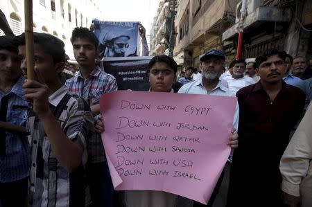 A Pakistani Shi'ite Muslim boy holds a sign with others to condemn Saudi Arabia over its intervention in Yemen, during a protest organized by religious group Majlis-e-Wahdat-e Muslimeen (MWM) in Karachi March 27, 2015. REUTERS/Akhtar Soomro