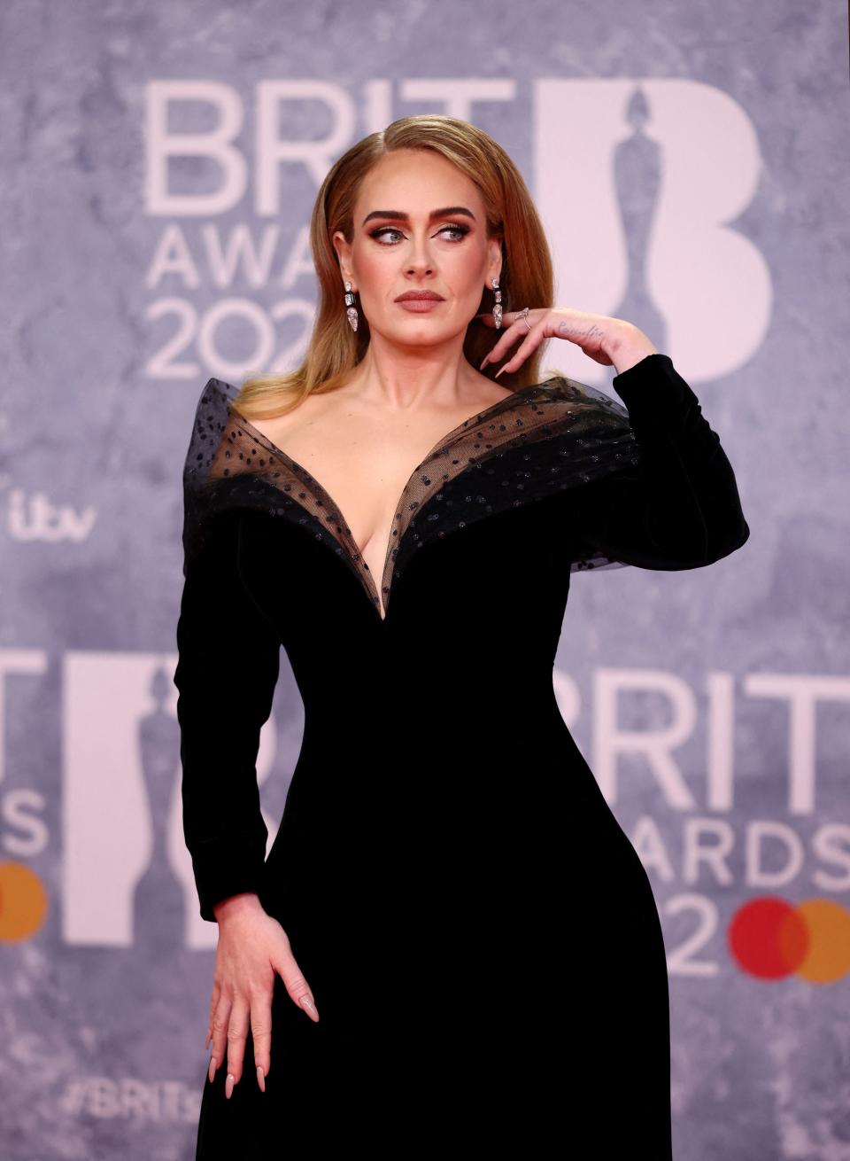 adele wearing a black off the shoulder gown at the 2022 brit awards