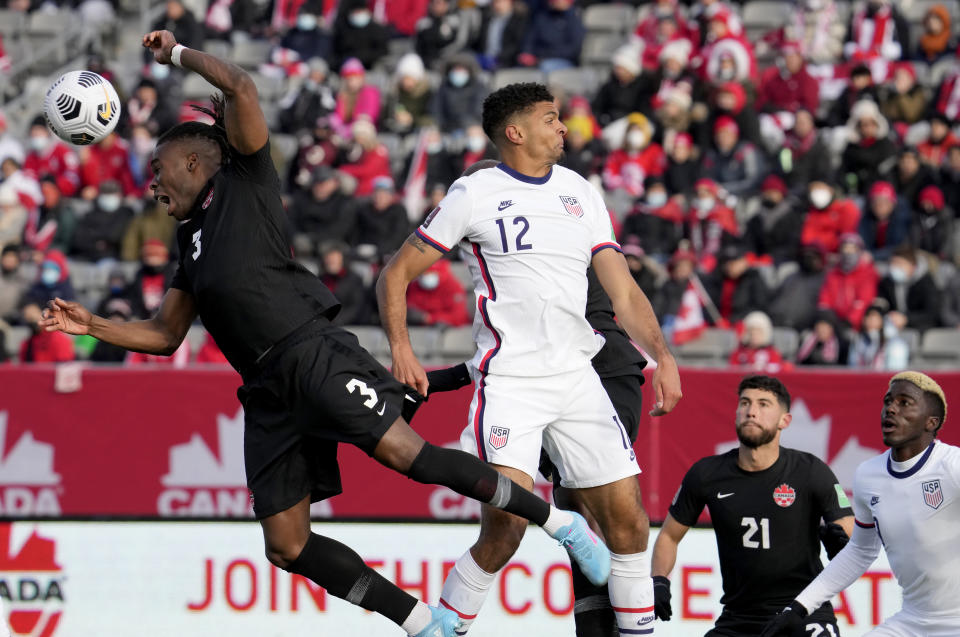 Canada's Samuel Adekugbe (3) makes a header as United States' Miles Robinson (12), Canada's Jonathan Osorio (21) and United States' Gyasi Zardes, right, look on during the first half of a World Cup soccer qualifier in Hamilton, Ontario, Sunday, Jan. 30, 2022. (Frank Gunn/The Canadian Press via AP)
