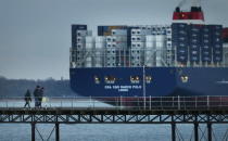 SOUTHAMPTON, ENGLAND - DECEMBER 10: People walk on a pier at Hythe as The Marco Polo, the world's biggest container ship, leaves Southampton on December 10, 2012 in England. On its first visit to Europe, the 54m (177ft) wide and 396m (1299ft) long container ship - which is 51m (167ft) longer than the Queen Mary II - will mostly carry consumer goods for delivery to shops for Christmas. (Photo by Peter Macdiarmid/Getty Images)