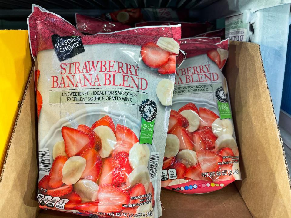 Two packages of frozen strawberries and bananas in a cardboard box