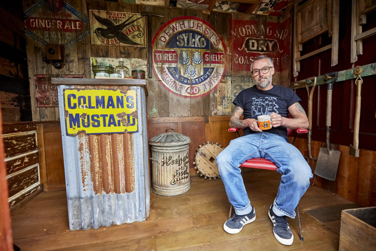 Man sits inside the shed he made