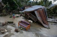 Residents clean up next to their damaged house in New Bataan town on December 5, 2012, a day after Typhoon Bopha hit the province. The Philippine government said typhoon gusts of up to 210 kilometres (130 miles) an hour had destroyed thousands of homes and other buildings, leaving residents with little more than the clothes on their backs